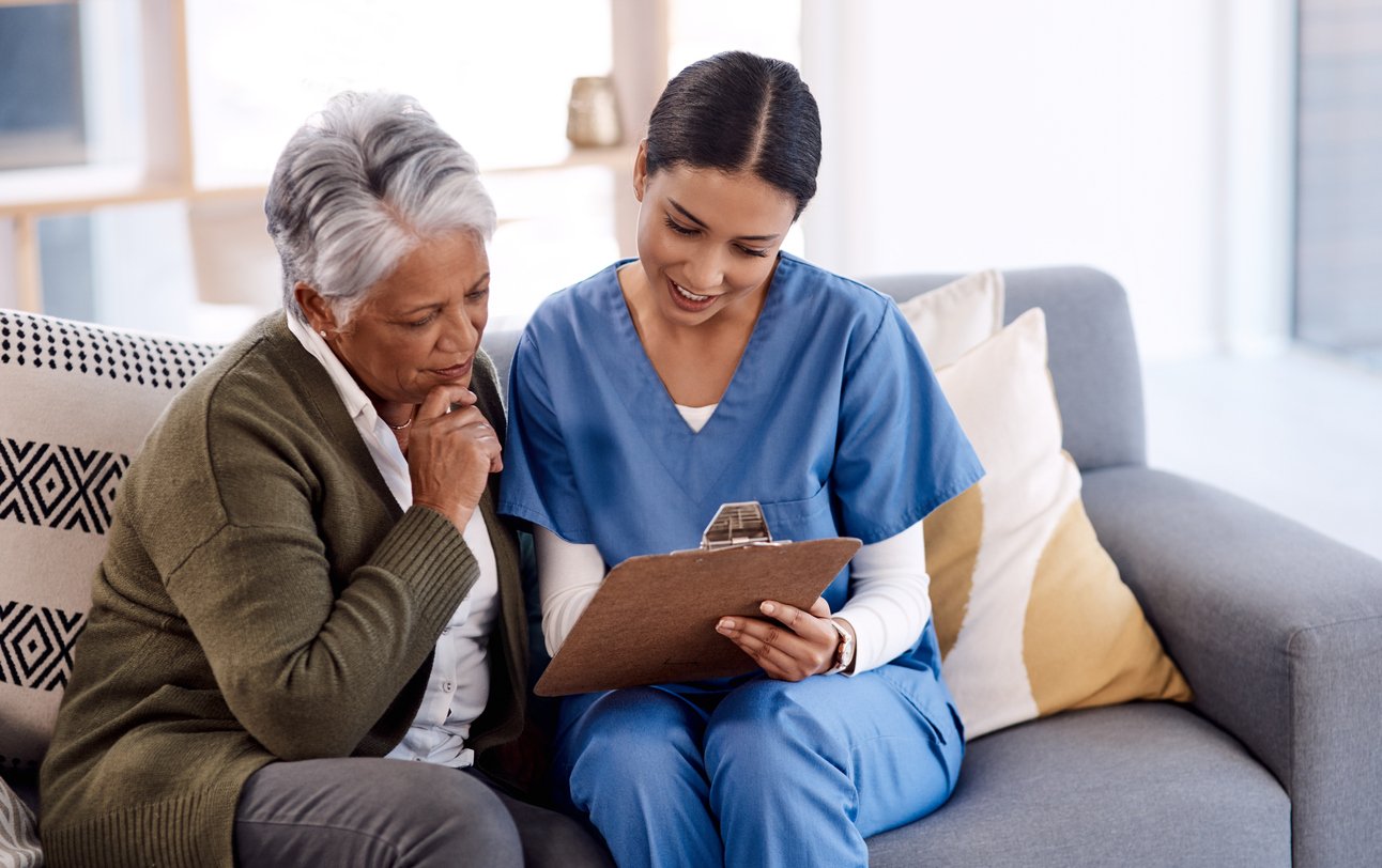 Black senior citizen reviewing her health coverage plan with a nurse in scrubs